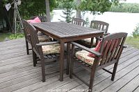 Full view of rectangular teak table and six matching chairs on wood deck by lake