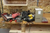 Various power tools including drill, sanders, circular saw, edge joiner kit box, socket set, and metal sander case laid out on a wooden workbench.