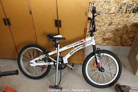 Side view of white Blade Aggressor single speed bike with black and red accents, 20 inch tires, dual hand brakes, and black/white seat.