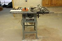 Front view of table saw mounted on stand showing table top and blade guard