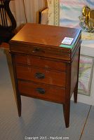 Closed view of the walnut sewing cabinet showing its rectangular shape, lift top, and two drawers with metal handles.