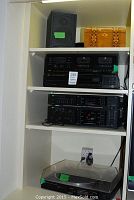 Shelved stereo components including JVC double cassette deck, CD player, Sansui receiver, Sansui turntable under transparent dust cover.