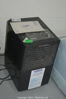 Black DeLonghi dehumidifier with vents on front and control dial on top, showing device condition and overall appearance.