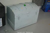 View of the exterior of the vintage painted trunk showing light blue color, metal latches, and some paint wear.