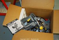 View of the miter saw packed inside the original box with styrofoam inserts and instruction manual visible.