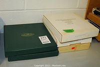 Three original boxes containing the five collector plates. Boxes include one green box featuring Anna Perenna branding and two white boxes labeled for contents.