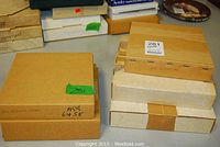 Boxes of the five collector plates in varying sizes and conditions, some showing wear and tape.