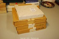 Four boxed Norman Rockwell collector plates stacked, with labels showing plate titles