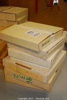 Stack of six collector plate boxes on a table, some labeled with plate titles.