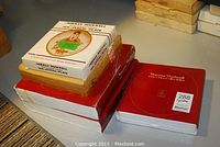 Boxes containing the Rockwell collector plates stacked on a table, showing some original packaging with printed titles and years.