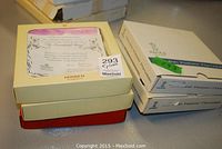 Stacked boxes of collector plates including original packaging with labels and certificates.