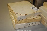 Three stacked boxes containing collector plates; boxes labeled with names 'Christy's Kitty' and 'Patrick's Puppy'.