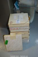 Photo of the stacked original boxes of the 10 Norman Rockwell Society collector plates showing some wear and labels with plate titles.
