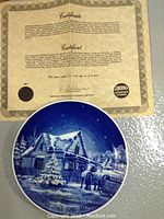 Certificate of authenticity for one of the plates showing Sorrina Products Limited, Kitchener, Ontario, and copyright date 1981 with depiction of a snowy Christmas cabin scene.
