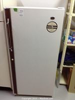 Closed view of white Woods upright freezer with brown handle and sticker on front door.