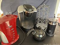 All five items grouped: Keurig brewer, red kettle, pod carousel, milk frother, teapot
