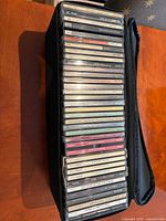Stack of approximately 35 jewel-case CDs inside black zip case