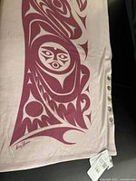 Full view of soft pink wrap showing Salish design and button edge