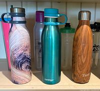 Front view of three stainless bottles on shelf