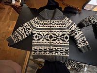 Front view of wool sweater laid flat showing geometric pattern and zipper.