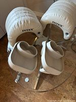 Four Intex accessories on glass table: two headrests and two trays