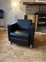 Front view of black faux leather club chair with square arms and metal legs