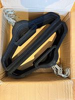 Open box showing stacked black Neatfreak hangers with silver hooks visible