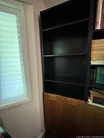 Full view showing black bookcase with shelves and lower doors