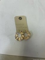 Photo of two gold plated crinkle hoop earrings on an Anthropologie branded tag.