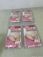 Four packages of Carole Martin full back coverage panties, beige color, displayed on table.