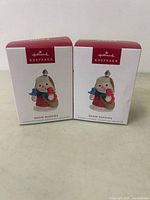 Two boxed Hallmark Keepsake Snow Buddies ornaments side by side on a flat surface.