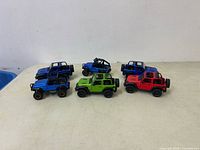 Front view of six diecast Jeep Wranglers and off-road vehicle models in various colors on plain background.