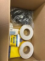 Box containing two paper towels rolls, a tub of WD-40 Specialist Butter Compound, a garden soil/fertilizer bag, and several small boxed items.