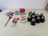 Overview of Makita and Hilti tool accessories on table including drill chucks, drill bit boxes, and chuck key.