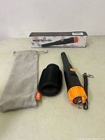 Handheld metal detector displayed with carrying pouch, belt holster, and original box on table.