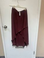 Full view of maroon Remans pull-up skirt hanging on a hanger, showing length and layering.