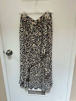 Full view of the Remans sleep pull up skirt hanging on a hanger, showing black and white abstract leaf pattern, mid-length with ruffled bottom edge.