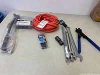Overview of all items on table including clamps, extension cord, socket, crimper, screws pack.
