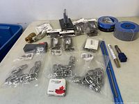 Overview of lot showing metal swivel snap hooks, drill bits, brass valve, clamps, and tape.
