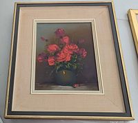 Framed and matted oil painting of red roses in a vase on a table with artist's signature visible