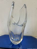 Front view of the clear art glass vase showing its abstract sculptural organic form with two upward pointed edges and a thick solid base.