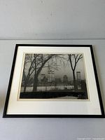 Full view of framed black and white photograph showing Montreal skyline with trees in foreground, matted and framed in black.