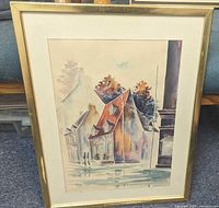 Framed watercolor painting showing Quebec street scene with historic buildings and autumn trees under glass in gold-tone frame.
