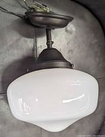 Opaque white rounded rectangular glass ceiling fixture with dark metal mounting base and wiring visible, shown from side angle