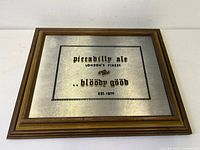 Wood framed vintage mirrored metal pub sign 'Piccadilly ale London's finest .. bloody good Est. 1879' measuring approximately 17" x 14"