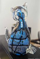 Front angled view of Murano glass cat paperweight showing blue and black internal abstract design.