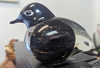 Close-up photo of black Murano glass bird sculpture showing gold flecks inside and smooth glossy finish