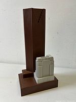 Side view of the figural savings bank showing the taller brown building and the shorter white building on a brown base.