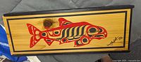 Top view of the rectangular cedar wood box showing the painted salmon design in red and black in Haida style with a wooden knob.