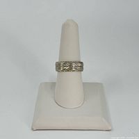 Front view of ring on white display stand showing full band pattern